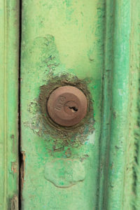 Vanishing Malta IV shows a 35mm digital colour image of a rusting lock on a dirty and dilapidated door.