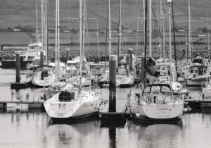 This Dingle Peninsula Ireland image shows a 35mm black and white film photograph of yachts moored in Dingle harbour