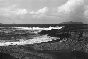 Dingle Peninsula Ireland shows 35mm black and white film photograph of the seashore and white waves and stoney beach near Dunquin 