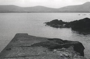 A 35mm black and white film photograph showing the pier at Winestrand on the Dingle peninsula