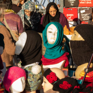 Headgear in various shapes and colours on display on the stalls and on some women at an outdoor market in London England