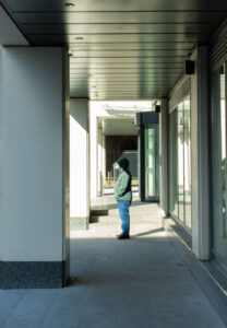 Triangle of Light captures a moment when a worker steps out of his workplace onto the pavement to have a cigarette.  As the title suggests, he is caught in a triangle of light formed by the building's overhang and the pavement.