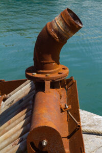 A 35mm digital colour photographic image of a rusting boat engine exhaust in the harbour at Balbriggan in Co Dublin