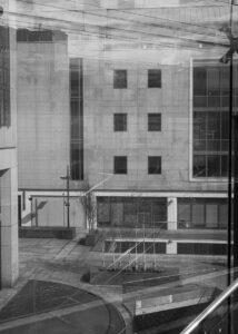 A black and white digital photographic image of buildings seen through glass during a stroll through the Dublin Docklands' area.